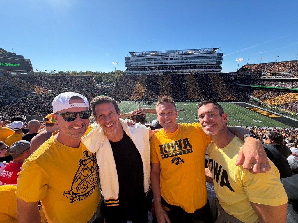 Friends together in the stands at Kinnick Stadium, wearing Iowa Hawkeyes colors